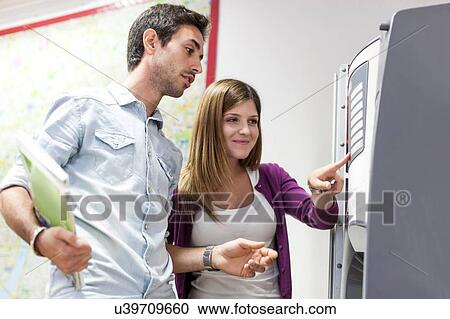 Young man and woman using vending machine View Large Photo Image Stock Image - Young man and woman using vending machine. Fotosearch
