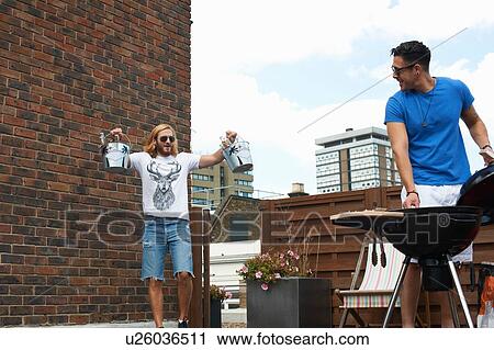 Young man carrying ice buckets at rooftop barbecue View Large Photo Image Stock Image - Young man carrying ice buckets at rooftop barbecue. Fotosearch