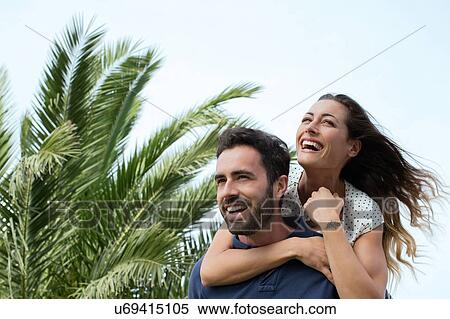 Stock Photography - Young man giving girlfriend a piggy back. Fotosearch