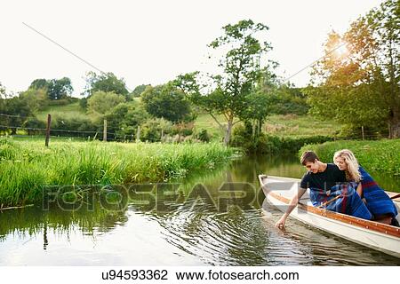 Young man with girlfriend touching water from river rowing boat View Large Photo Image Stock Image - Young man with girlfriend touching water from river rowing boat. Fotosearch