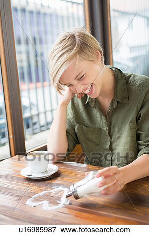 Young woman drawing sugar heart shape on cafe table View Large Photo Image Stock Photo - Young woman drawing sugar heart shape on cafe table. Fotosearch