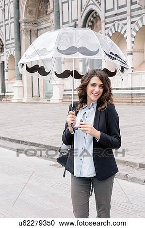 Young woman holding umbrella looking at camera smiling, Piazza Santa Maria Novella, Florence, Tuscany, Italy View Large Photo Image Stock Image - Young woman holding umbrella looking at camera smiling, Piazza Santa Maria Novella, Florence, Tuscany, Italy. Fotosearch