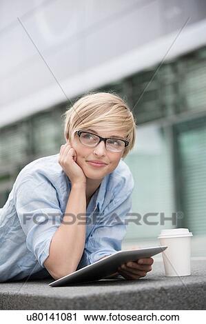 Young woman leaning on wall using digital tablet View Large Photo Image Stock Image - Young woman leaning on wall using digital tablet. Fotosearch