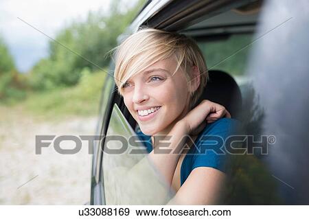 Young woman looking out of open car window View Large Photo Image Stock Photo - Young woman looking out of open car window. Fotosearch