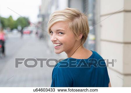 Young woman looking over her shoulder whilst strolling in city View Large Photo Image Stock Image - Young woman looking over her shoulder whilst strolling in city. Fotosearch