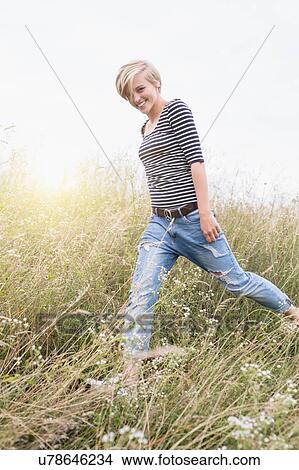 Picture - Young woman running in long grass. Fotosearch