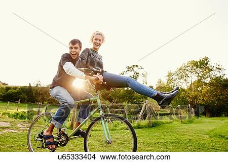 Young woman sitting on boyfriends bicycle handlebars View Large Photo Image Picture - Young woman sitting on boyfriends bicycle handlebars. Fotosearch