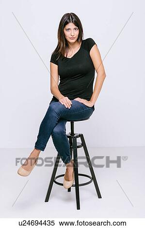 Young woman sitting on stool looking at camera pouting View Large Photo Image Stock Photography - Young woman sitting on stool looking at camera pouting. Fotosearch
