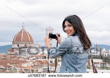 Stock Photo - Young woman taking photo of Florence Cathedral and Giotto's Campanile looking over shoulder smiling, Florence, Tuscany, Italy. Fotosearch