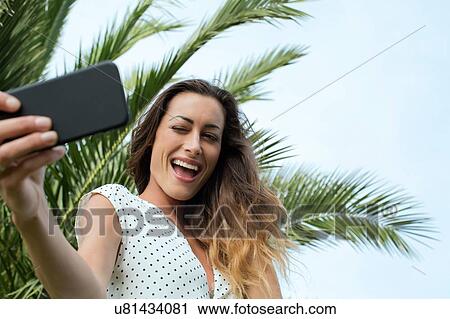 Young woman taking smartphone selfie View Large Photo Image Stock Image - Young woman taking smartphone selfie. Fotosearch