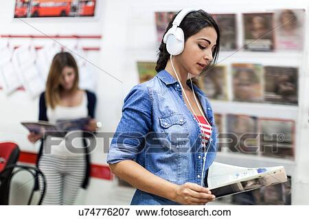 Stock Photo - Young woman wearing headphones, studying. Fotosearch