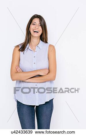Young woman wearing shirt and skinny jeans arms crossed looking at camera smiling View Large Photo Image Stock Photo - Young woman wearing shirt and skinny jeans arms crossed looking at camera smiling. Fotosearch