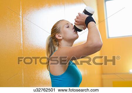 Young woman, wearing sports clothing, drinking from water bottle View Large Photo Image Stock Image - Young woman, wearing sports clothing, drinking from water bottle. Fotosearch