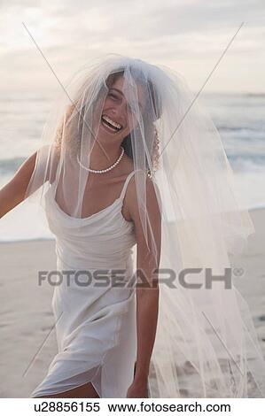 Young woman wearing wedding dress and veil, fooling around on beach View Large Photo Image Stock Photography - Young woman wearing wedding dress and veil, fooling around on beach. Fotosearch