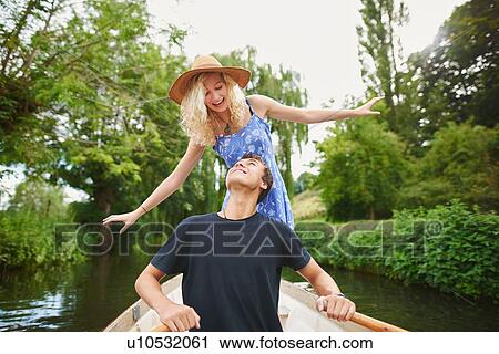 Young woman with boyfriend standing in rowing boat on river View Large Photo Image Stock Image - Young woman with boyfriend standing in rowing boat on river. Fotosearch