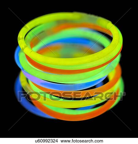 Stock Illustration - Glowstick bangles against a black background.. Fotosearch