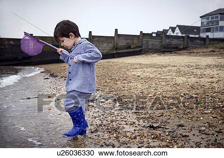 MODEL RELEASED. Boy wearing wellington boots on the beach holding fishing net. View Large Photo Image Stock Image - MODEL RELEASED. Boy wearing wellington boots on the beach holding fishing net.. Fotosearch