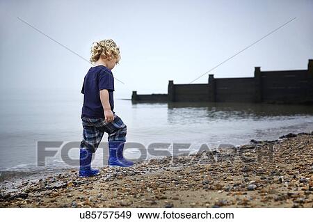 MODEL RELEASED. Boy wearing wellington boots walking on the beach. View Large Photo Image Stock Photo - MODEL RELEASED. Boy wearing wellington boots walking on the beach.. Fotosearch
