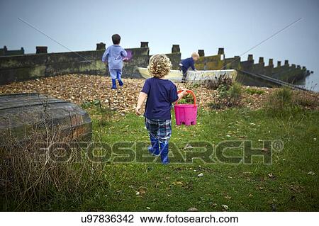 MODEL RELEASED. Boys playing on the beach, one holding bucket. View Large Photo Image Stock Image - MODEL RELEASED. Boys playing on the beach, one holding bucket.. Fotosearch