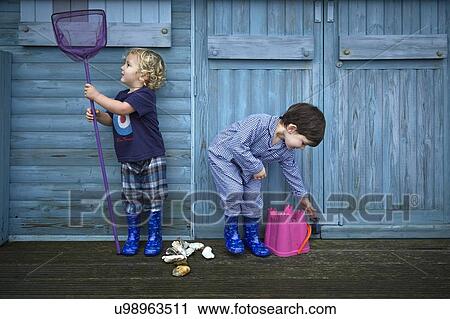 MODEL RELEASED. Two boys playing in front of beach hut with fishing net and bucket. View Large Photo Image Stock Image - MODEL RELEASED. Two boys playing in front of beach hut with fishing net and bucket.. Fotosearch