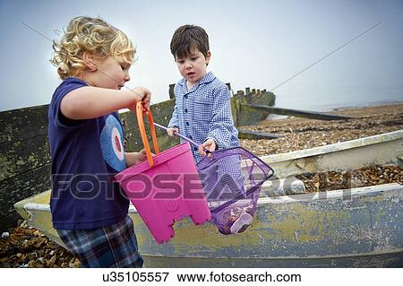 MODEL RELEASED. Two boys playing on the beach with bucket and fishing net. View Large Photo Image Stock Photo - MODEL RELEASED. Two boys playing on the beach with bucket and fishing net.. Fotosearch