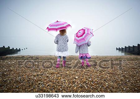 MODEL RELEASED. Two girls on the beach holding umbrellas. View Large Photo Image Stock Image - MODEL RELEASED. Two girls on the beach holding umbrellas.. Fotosearch