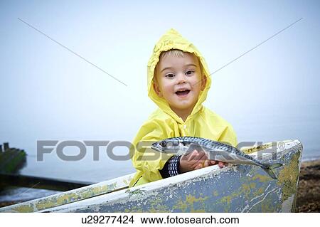 MODEL RELEASED. Young boy wearing raincoat holding a mackerel, portrait. View Large Photo Image Picture - MODEL RELEASED. Young boy wearing raincoat holding a mackerel, portrait.. Fotosearch