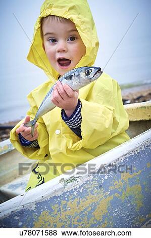 MODEL RELEASED. Young boy wearing raincoat holding a mackerel, portrait. View Large Photo Image Stock Photo - MODEL RELEASED. Young boy wearing raincoat holding a mackerel, portrait.. Fotosearch