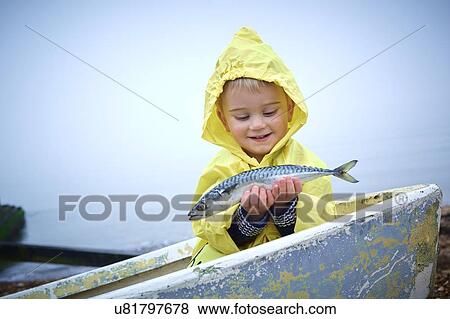 MODEL RELEASED. Young boy wearing raincoat holding a mackerel, portrait. View Large Photo Image Stock Photo - MODEL RELEASED. Young boy wearing raincoat holding a mackerel, portrait.. Fotosearch