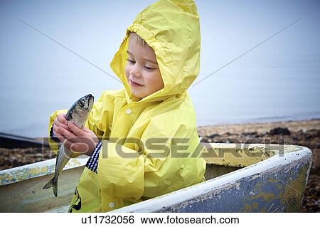 MODEL RELEASED. Young boy wearing raincoat holding a mackerel, portrait. View Large Photo Image Stock Photograph - MODEL RELEASED. Young boy wearing raincoat holding a mackerel, portrait.. Fotosearch