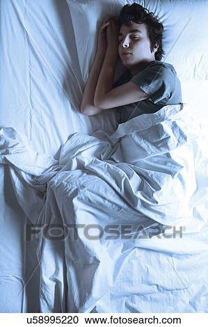 Stock Image - MODEL RELEASED. Young man asleep in a bed.. Fotosearch