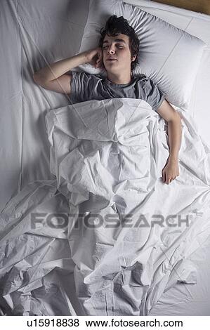 Stock Photo - MODEL RELEASED. Young man asleep in a bed.. Fotosearch