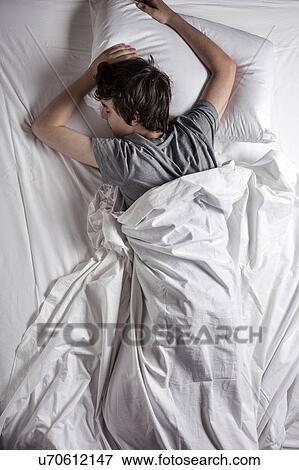 Stock Photo - MODEL RELEASED. Young man asleep in a bed.. Fotosearch