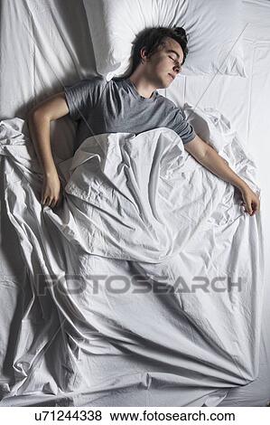 Stock Photo - MODEL RELEASED. Young man asleep in a bed.. Fotosearch