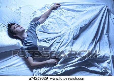 MODEL RELEASED. Young man asleep in a bed. View Large Photo Image Stock Photo - MODEL RELEASED. Young man asleep in a bed.. Fotosearch