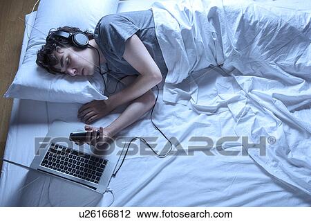 MODEL RELEASED. Young man asleep in bed with laptop and phone. View Large Photo Image Stock Image - MODEL RELEASED. Young man asleep in bed with laptop and phone.. Fotosearch