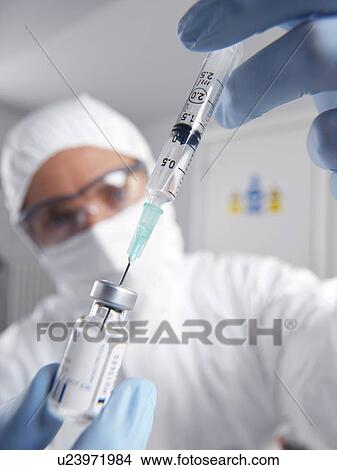 PROPERTY RELEASED. MODEL RELEASED. Doctor filling a syringe from a sealed vial of a drug or vaccine. View Large Photo Image Picture - PROPERTY RELEASED. MODEL RELEASED. Doctor filling a syringe from a sealed vial of a drug or vaccine.. Fotosearch