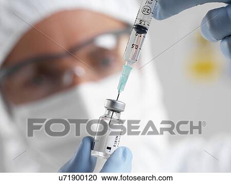 PROPERTY RELEASED. MODEL RELEASED. Doctor filling a syringe from a sealed vial of a drug or vaccine. View Large Photo Image Stock Image - PROPERTY RELEASED. MODEL RELEASED. Doctor filling a syringe from a sealed vial of a drug or vaccine.. Fotosearch