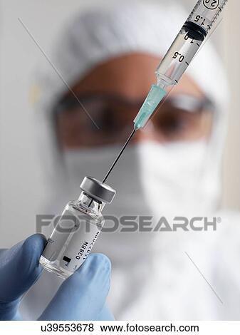 PROPERTY RELEASED. MODEL RELEASED. Doctor filling a syringe from a sealed vial of a drug or vaccine. View Large Photo Image Stock Photo - PROPERTY RELEASED. MODEL RELEASED. Doctor filling a syringe from a sealed vial of a drug or vaccine.. Fotosearch