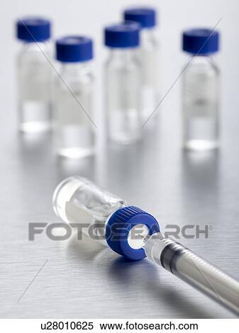 Stock Illustration - Vaccine vials and a syringe, close up.. Fotosearch