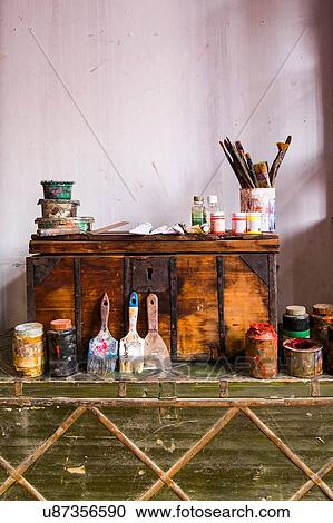 Stock Image - Art supplies and modern oil painting on wooden trunks. Fotosearch