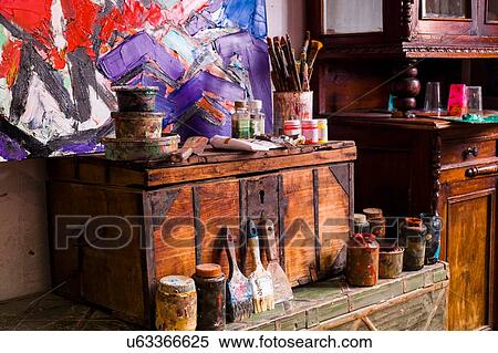 Stock Photography - Art supplies and modern oil painting on wooden trunks. Fotosearch