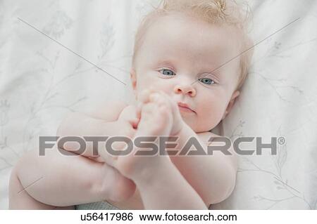 Baby girl, lying on back, holding feet View Large Photo Image Stock Photograph - Baby girl, lying on back, holding feet. Fotosearch