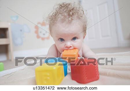 Stock Image - Baby girl playing with coloured blocks. Fotosearch