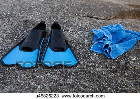 Stock Image - Blue swimming flippers and towel on beach. Fotosearch