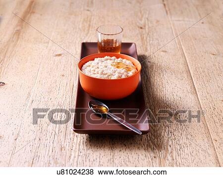 Stock Photo - Breakfast bowl of porridge with honey on wood. Fotosearch