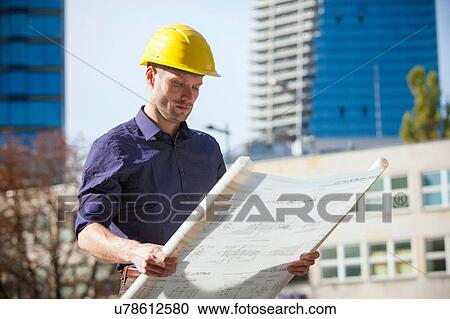 Building contractor wearing hard hat looking at blueprint View Large Photo Image Stock Image - Building contractor wearing hard hat looking at blueprint. Fotosearch