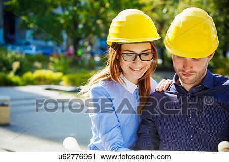 Stock Image - Building contractors wearing hard hats. Fotosearch