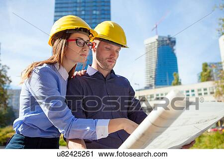 Building contractors wearing hard hats looking at blueprint View Large Photo Image Stock Image - Building contractors wearing hard hats looking at blueprint. Fotosearch