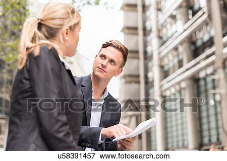 Stock Photo - Businessman and businesswoman meeting outside office building, London, UK. Fotosearch
